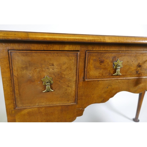 1002 - A Georgian style walnut kneehole desk, with leather inset top over three drawers and shaped apron, r... 