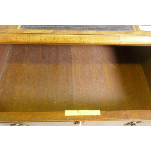 1002 - A Georgian style walnut kneehole desk, with leather inset top over three drawers and shaped apron, r... 