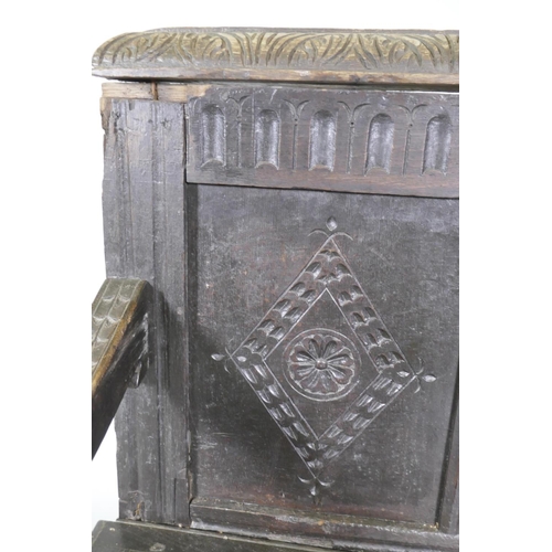 1007 - An C18th oak settle with carved panel back and front, lift up seat, raised on stile supports, with a... 