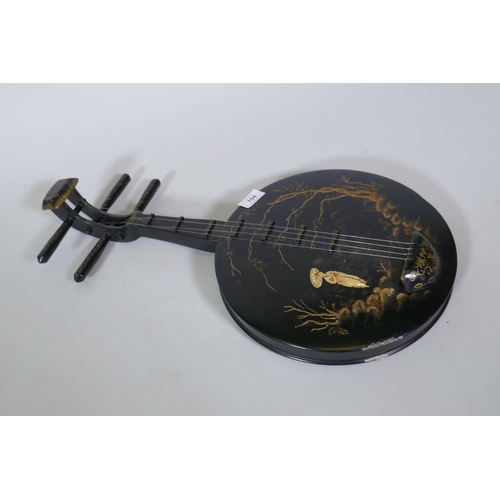 104 - A wood wall ornament with raised decoration, in the form of an Oriental stringed musical instrument,... 