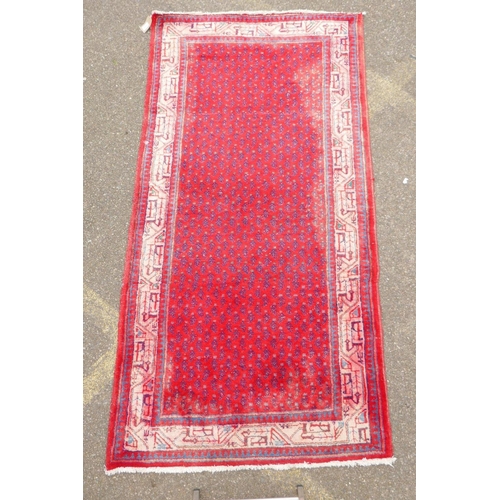 1051 - A Persian red ground wool Sarouk Mir rug, 208 x 108cm