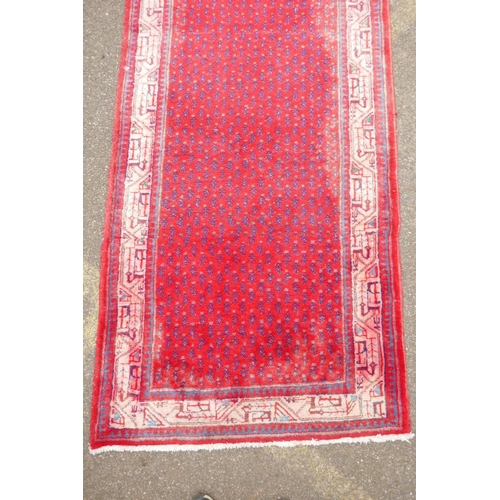 1051 - A Persian red ground wool Sarouk Mir rug, 208 x 108cm