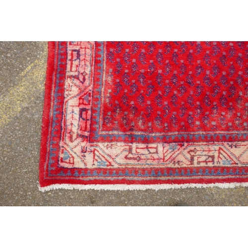 1051 - A Persian red ground wool Sarouk Mir rug, 208 x 108cm