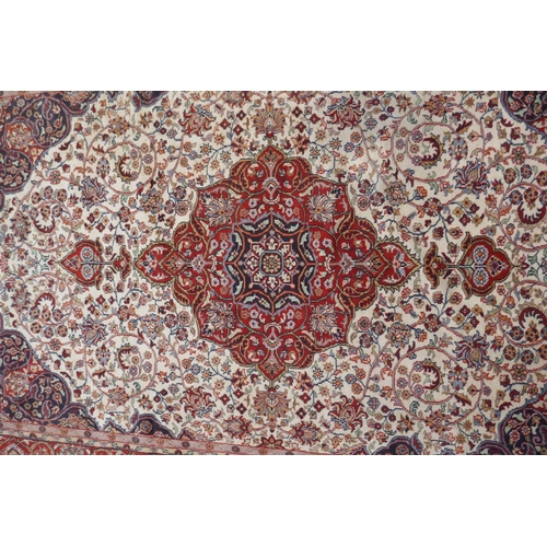 1052 - A Persian ivory ground wool Tabriz carpet with a floral medallion and red borders, 180 x 284cm