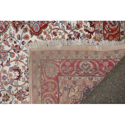 1052 - A Persian ivory ground wool Tabriz carpet with a floral medallion and red borders, 180 x 284cm