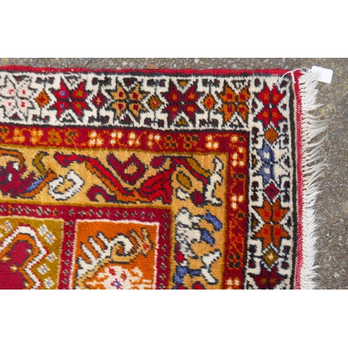 1058 - A rich red ground Caucasian rug with prayer mat design and multi-colour borders, 112 x 186cm