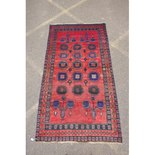 1064 - A vintage Persian Hamadan village rug with a unique design and colours on a red field, 140 x 256cm