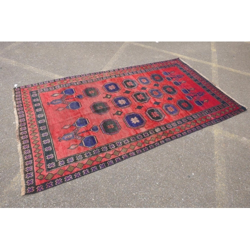 1064 - A vintage Persian Hamadan village rug with a unique design and colours on a red field, 140 x 256cm