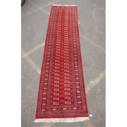 1068 - A rich red ground fine woven Bokhara runner, 98 x 364cm