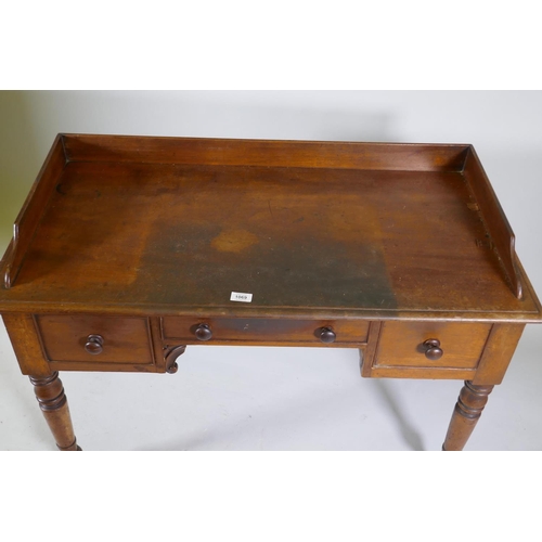 1069 - Early C19th mahogany kneehole desk of three drawers, with three quarter gallery top, raised on turne... 