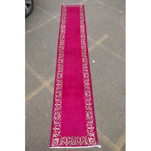 1071 - A large five hand woven Persian runner with a plain pink field and decorative border, 390 x 75cm