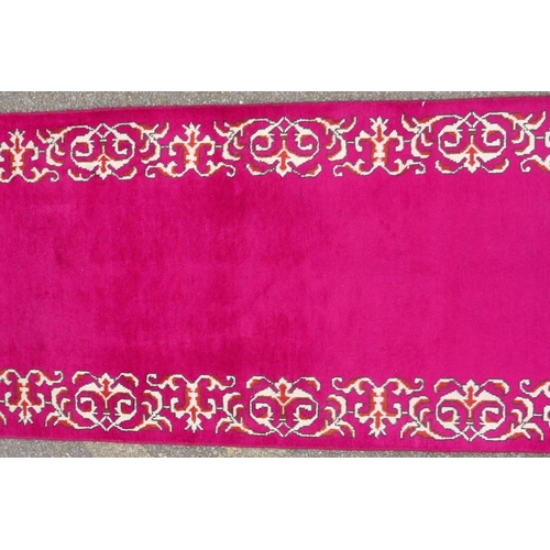 1071 - A large five hand woven Persian runner with a plain pink field and decorative border, 390 x 75cm