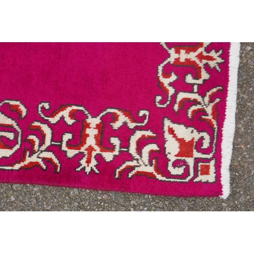 1071 - A large five hand woven Persian runner with a plain pink field and decorative border, 390 x 75cm