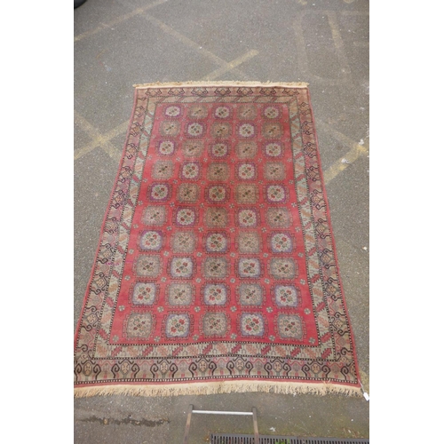 1072 - A hand woven Caucasian carpet with a bespoke all over Bokharra design on a salmon pink ground, 185 x... 