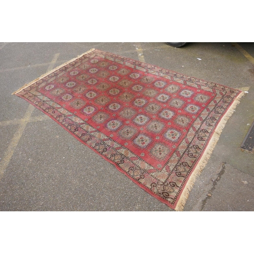 1072 - A hand woven Caucasian carpet with a bespoke all over Bokharra design on a salmon pink ground, 185 x... 