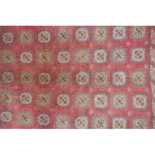 1072 - A hand woven Caucasian carpet with a bespoke all over Bokharra design on a salmon pink ground, 185 x... 