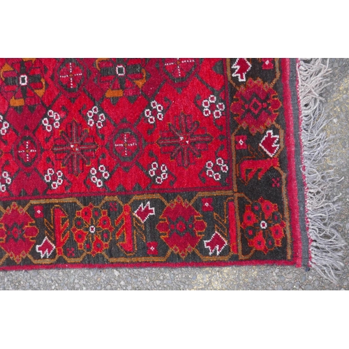 1082 - A rich red ground Persian wool runner with an allover geometric design and black borders, 84 x 290cm