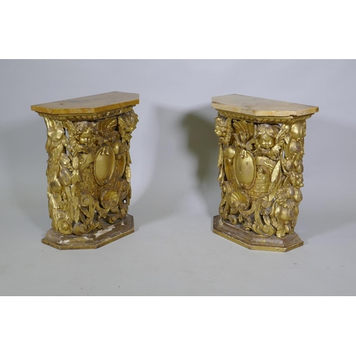 1084 - A pair of early C19th carved and giltwood pine pedestals/stands, decorated with winged putti and she... 