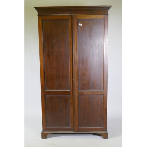 1085 - A late C19th/early C20th mahogany two door wardrobe/cupboard, with panelled doors, raised on bracket... 