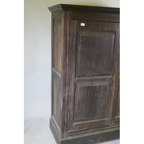 1101 - An early C18th two door cupboard with fielded panel doors and panelled sides, raised on a plinth bas... 