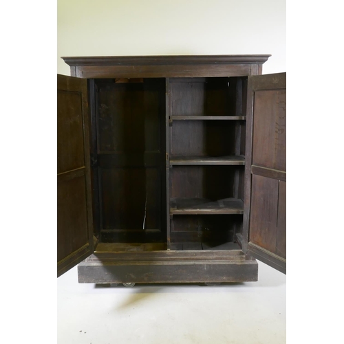 1101 - An early C18th two door cupboard with fielded panel doors and panelled sides, raised on a plinth bas... 