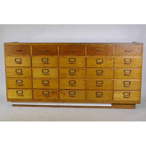 1110 - An oak haberdasher's shop cabinet with glass top and sliding doors, the back with five flights of fo... 