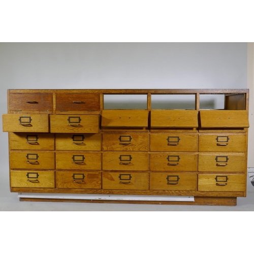 1110 - An oak haberdasher's shop cabinet with glass top and sliding doors, the back with five flights of fo... 