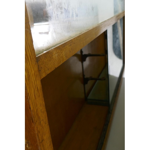 1110 - An oak haberdasher's shop cabinet with glass top and sliding doors, the back with five flights of fo... 