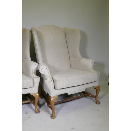 1117 - A good pair of Georgian style high back wing armchairs with wide seats, raised on walnut cabriole su... 