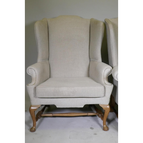 1117 - A good pair of Georgian style high back wing armchairs with wide seats, raised on walnut cabriole su... 