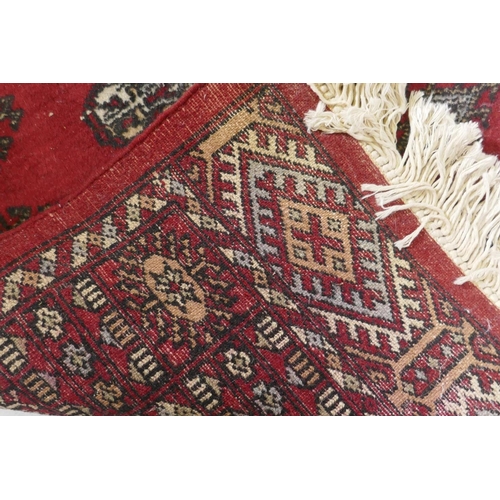 1130 - A Bokhara hand woven wool rug, red ground with traditional pattern, 7 x 157cm