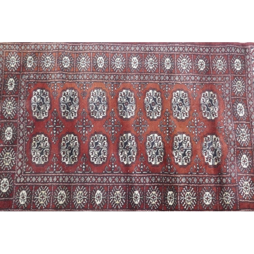 1131 - A Bokhara hand woven deep red ground rug with traditional pattern, 130 x 80cm