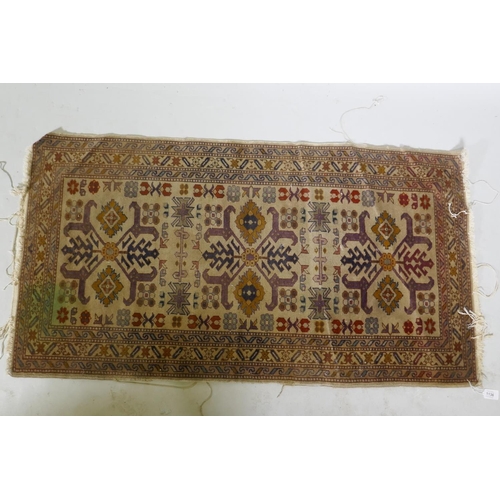 1136 - An antique hand woven Oriental rug with geometric designs n a buff coloured field, 68 x 125cm