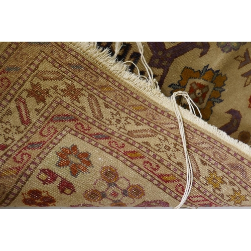 1136 - An antique hand woven Oriental rug with geometric designs n a buff coloured field, 68 x 125cm