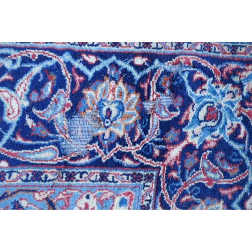 1139 - A large Persian red ground wool carpet with floral medallion design and blue borders, some wear, 74 ... 