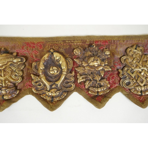 180 - A Tibetan silk and linen belt with bronze mounts depicting the eight Buddhist treasures, 72cm long