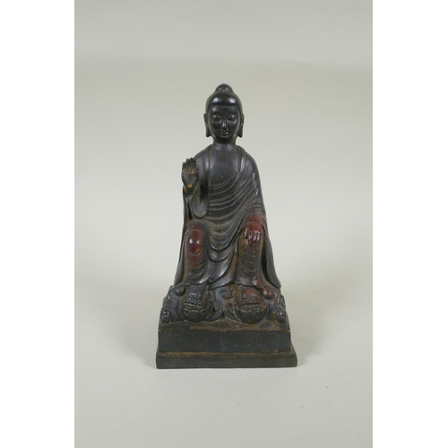 188 - A Chinese bronze Buddha seated on a throne, with the remnants of gilt and copper patina, 23cm high