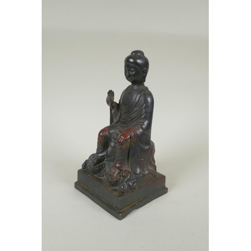 188 - A Chinese bronze Buddha seated on a throne, with the remnants of gilt and copper patina, 23cm high