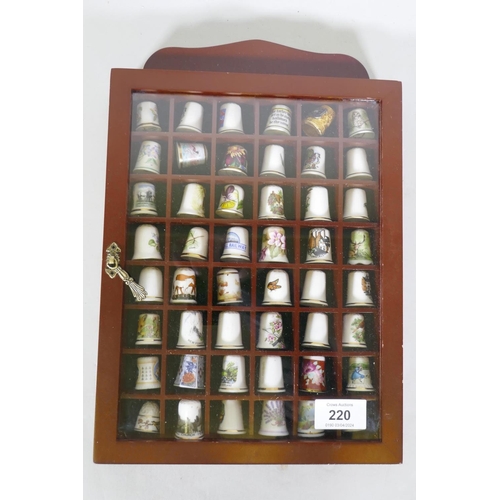 220 - A collection of 48 porcelain thimbles in a display case, 32 x 22 x 4cm