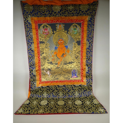 262 - A Tibetan painted thangka depicting Jambhala, housed within a silk mount, 80 x 124cm