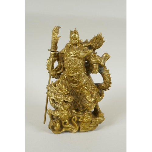 273 - A Chinese gilt bronzed metal figure of Guan Yin standing on the back of a dragon, 22cm high