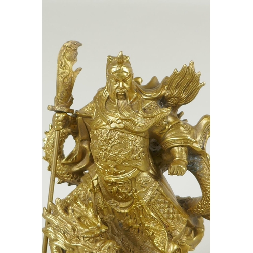 273 - A Chinese gilt bronzed metal figure of Guan Yin standing on the back of a dragon, 22cm high