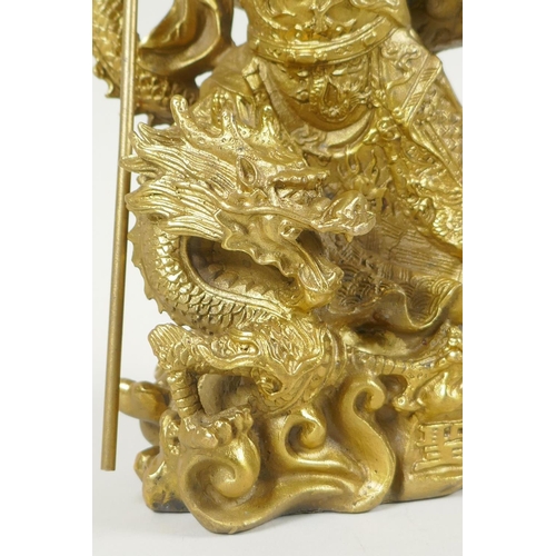 273 - A Chinese gilt bronzed metal figure of Guan Yin standing on the back of a dragon, 22cm high