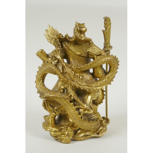 273 - A Chinese gilt bronzed metal figure of Guan Yin standing on the back of a dragon, 22cm high