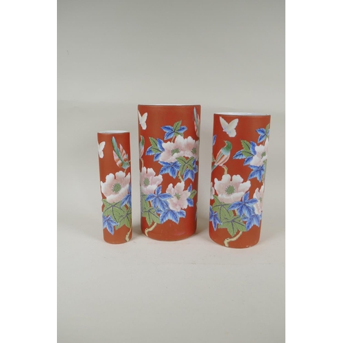 302 - A graduated set of three Chinese iron red ground porcelain cylinder vases with floral decoration, AF... 