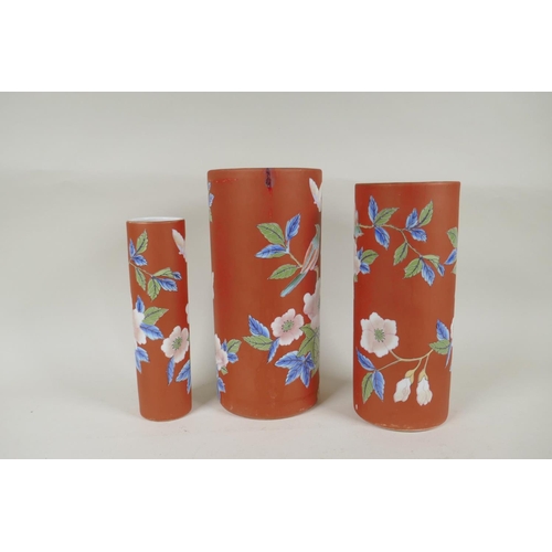 302 - A graduated set of three Chinese iron red ground porcelain cylinder vases with floral decoration, AF... 