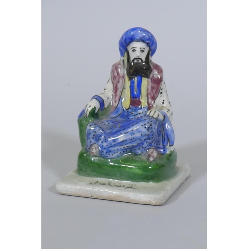 67 - An antique Persian Qajar pottery figure of a scholar, possibly Omar Khayyam, with inscription to bas... 