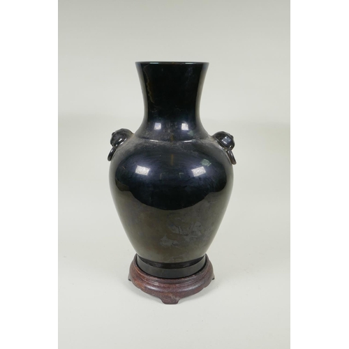 78 - A Chinese treacle glazed porcelain vase with two mask handles, YongZheng mark to base, on a hardwood... 