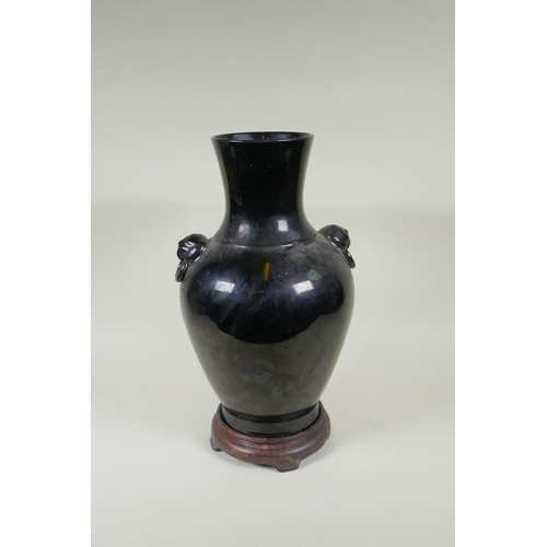 78 - A Chinese treacle glazed porcelain vase with two mask handles, YongZheng mark to base, on a hardwood... 