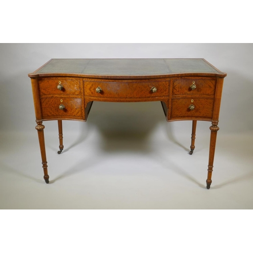 1009 - A Victorian satinwood serpentine front five drawer kneehole dressing table, with inset leather top, ... 